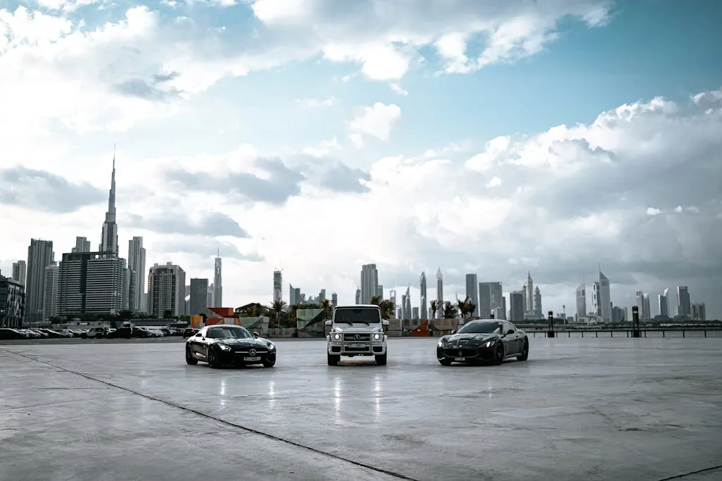 Three luxury cars parked with Dubai skyline and Burj Khalifa in the background.